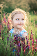 Little girl on nature in summer in a field with a bouquet of flowers in her hands.