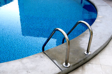 Grab bars ladder in the blue swimming pool