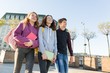 © Valerii Honcharuk - Smiling teens students with backpacks and textbooks, talking and going forward.