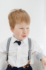 Emotional Little Caucasian Boy Grimace Portrait. Funny Redhead Child Sitting on Chair Isolated on White Background. Kid Model with Scowly Face Frown. Adorable Toddler Play Ape Front Shot