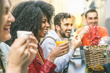 meeting of schoolmates having fun together on an outdoors cafeteria. Focus on the afro girl drinking fruit juice. Boys and girls leisure activities lifestyle concept