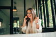 © bnenin - Smiling millennial entrepreneur talking on mobile phone at modern office.