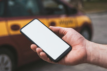 Mock Up Of A Smartphone In Hand, On The Background Of A Taxi Car.
