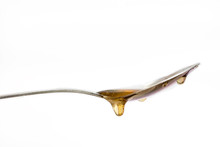 Honey Dripping From A Silver Spoon On Isolated White Background