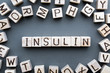 the word insulin wooden cubes with burnt letters, hormone insulin, diabetes treatment  gray background top view, scattered cubes around random letters