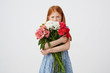 © timtimphoto - Portrait of little offended freckles red-haired girl, malcontent looks awey, holds bouquet and covers face with him, wears in blue dress, over white background.