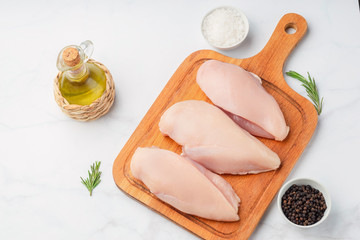 Raw uncooked chicken fillet on a cutting table with ingredients for cooking