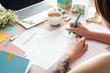 © LIGHTFIELD STUDIOS - cropped view of woman sitting behind wooden table with laptop and stationery, writing in paper planners
