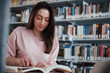 © standret - Some interesting information. Brunette girl in casual clothes having good time in the library full of books