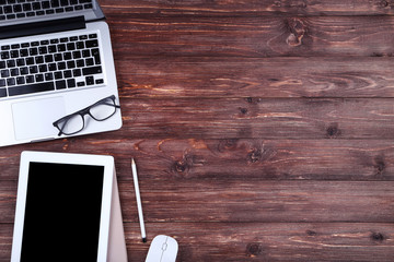 Laptop and tablet computer with glasses and mouse on wooden table