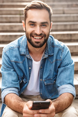 Sticker - Smiling young man sitting on stairs outdoors