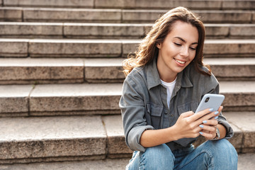 Poster - Cheerful young girl sitting on stairs outdoors