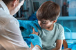 pediatrician vaccinating little boy in the pediatric clinic / doctor holding syringe subcutaneous vaccine for child in the medical office 