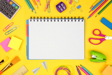 Wall Mural - Blank graphing paper notebook with school supplies frame against a yellow background. Back to school concept. Copy space.