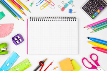 Blank graphing paper notebook with school supplies frame against a white background. Back to school concept. Copy space.