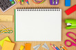 © Jenifoto - Blank coil notebook with school supplies frame against a wood desk background. Back to school concept. Copy space.