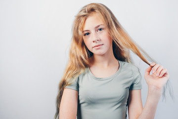 Portrait of pretty girl with long  blonde hair. Beautiful caucasian teen girl posing on grey background.