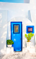 Beautiful old blue door, blue window on white facade of greek architecture and potted flowers, Santorini island, Greece, Europe. Beautiful details of the island of Santorini. Famous travel destination