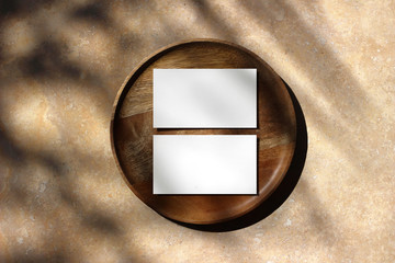 blank white business cards mockups on wooden plate. marble backgound with palm leaf shadow overlay. 