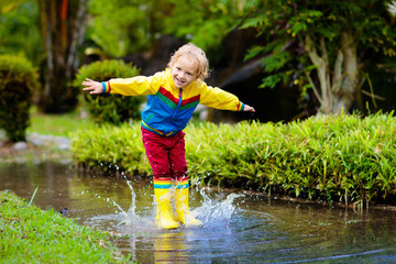 Wall Mural - Child playing in puddle. Kids jump in autumn rain