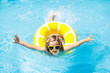 © famveldman - Child in swimming pool on ring toy. Kids swim.