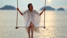 Beautiful Woman Playfully Enjoying Swing Hanging Over The Ocean, Eye Level Shot, Real Time, Blurred Background, Day