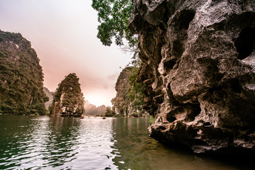 Boat cave tour in Trang An Scenic Landscape formed by karst towers and plants along the river (UNESCO World Heritage Site). It's Halong Bay on land of Vietnam. Ninh Binh province, Vietnam.