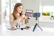 © Krakenimages.com - Beautiful young influencer woman recording make up video tutorial with a happy face standing and smiling with a confident smile showing teeth