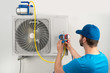 Installation service fix  repair maintenance of an air conditioner outdoor unit, by cryogenist technican worker evacuate the system with vacuum pump and manifold gauges in blue shirt baseball cap