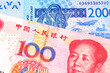 A close up image of a blue, West African franc bank note with a red, one hundred Chinese yuan bank note in macro
