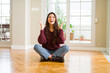 © Krakenimages.com - Young beautiful woman sitting on the floor at home celebrating mad and crazy for success with arms raised and closed eyes screaming excited. Winner concept