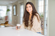 © Krakenimages.com - Beautiful young girl drinking a cup of coffee at home and smiling