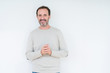 © Krakenimages.com - Elegant senior man over isolated background Hands together and fingers crossed smiling relaxed and cheerful. Success and optimistic