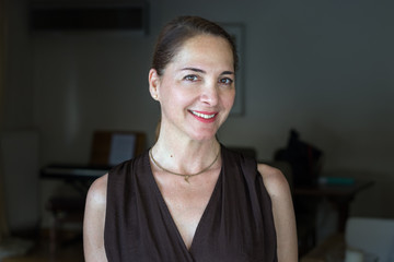 Portrait of a mature woman, 40s, smiling looking camera at her home.