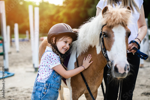 Fotografía Cute little girl and her older sister enjoying with pony horse outdoors at ranch
