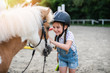 © hedgehog94 - Cute little girl enjoying with pony horse outdoors at ranch.