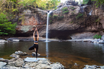 Young girl asian women is playing  yoga in front of the waterfall.