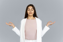 Calm Healthy Mindful Indian Business Woman Wear Suit Meditating Doing Yoga Exercise With Eyes Closed Breathing Fresh Air Relaxing Feel Zen No Stress Free Relief Isolated On Grey Studio Background