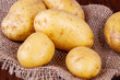 Surowe ziemniaki. Ziemniaki ze skorka na kuchennym stole. Worek z ziemniakami. 
