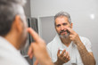 © cherryandbees - smiling middle aged bearded man applying face cream