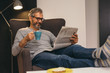 © cherryandbees - man reading newspaper at his apartment