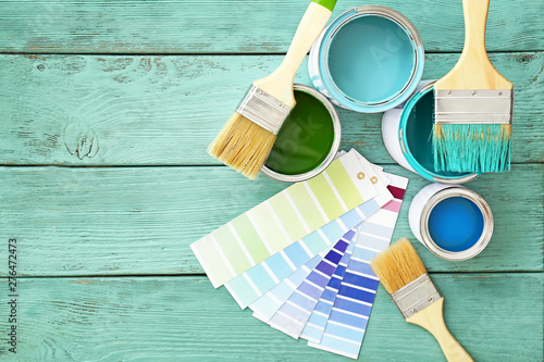 Fotografía Cans of paint with brushes and palette samples on wooden background