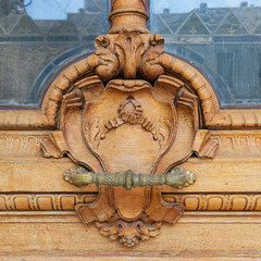 Closeup of wooden floral pattern engravings and handlebar on old door leaf