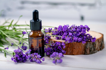 lavender herbal oil and flowers on wooden background