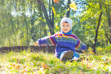 Wall Mural - boy in sweater and hat sitting on the grass