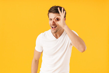 Poster - Photo of cheery man in basic t-shirt smiling at camera while showing ok sign