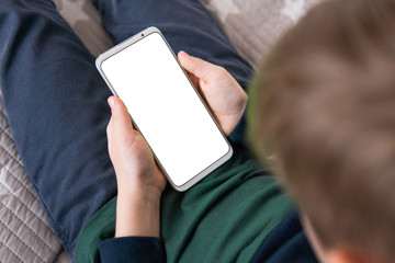 Wall Mural - Phone a for mock up is holding kid. close up top view Smartphone with a white screen in hand child . Smartphone with a mock up in the hands of a child.