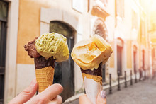 Two Hands Close-up Holding Cones With Italian Ice-cream Gelato On The Background Of Rome Streeet