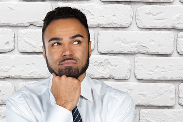 Wall Mural - Handsome young African American man looking up with thoughtful and skeptical expression