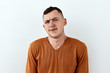 © PinkCoffee Studio - Skeptic and mistrust emotion Young man in orange sweater, portrait against white background